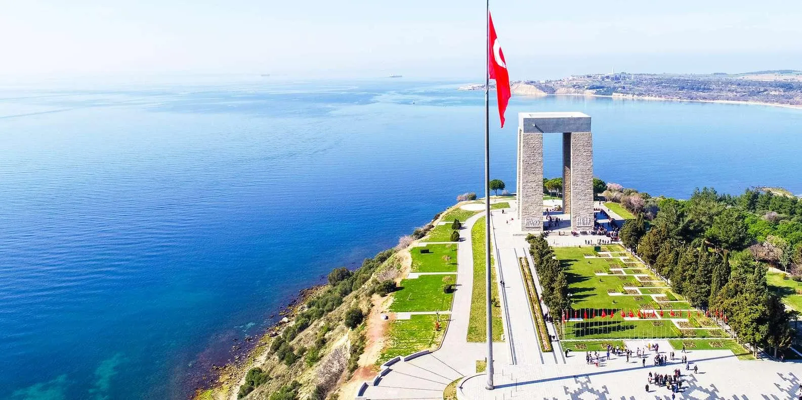 The tall Çanakkale Martyrs' Memorial and a Turkish flag above the sea